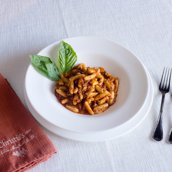 Christie's Italian cavatelli pasta with meat sauce and fresh basil on a white tablecloth.
