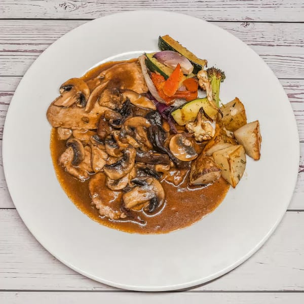 Chicken Marsala with mushrooms, roasted potatoes, and mixed vegetables on a white plate.